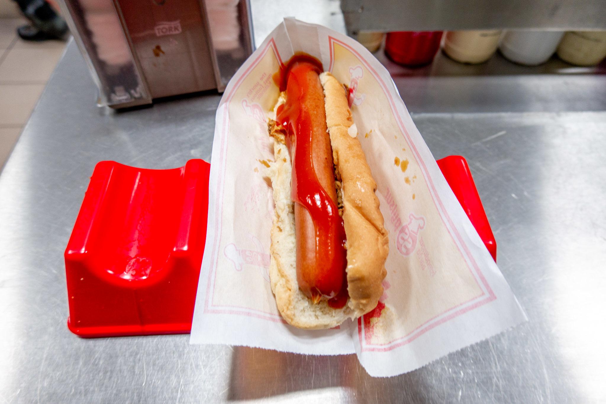 A hot dog in a paper wrapper with ketchup