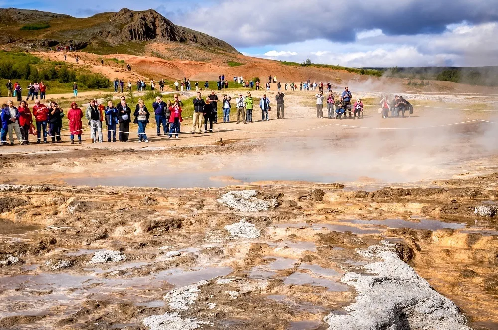 Group of people standing near a geyser