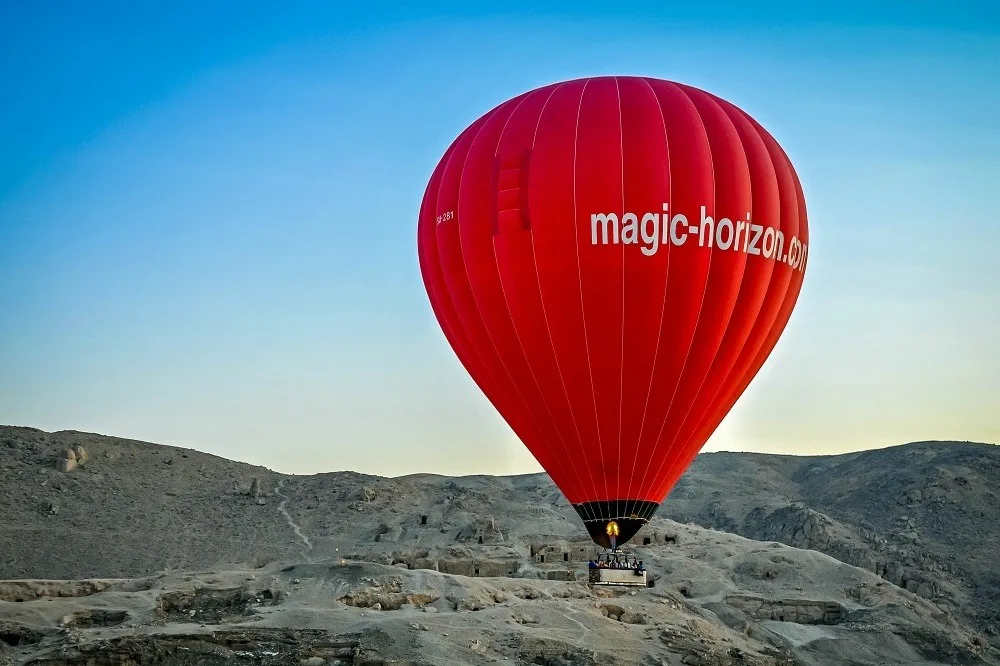 Bright red hot air balloon in Egypt taking off