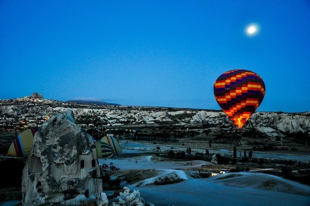 One of the Cappadocia Hot Air Balloons illuminated in the night sky under the moon