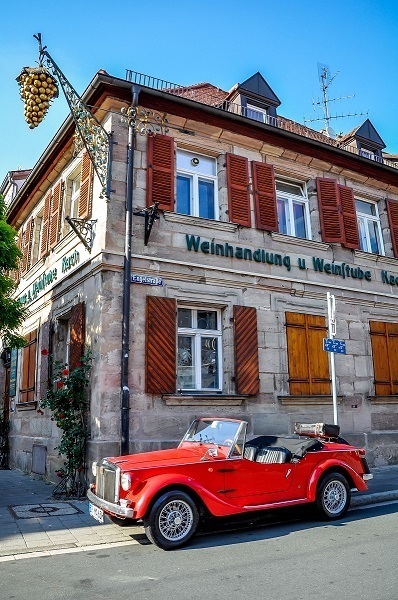 Red classic car in front of building