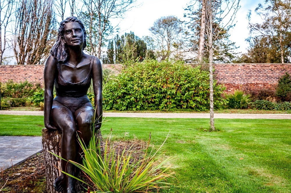 Statue of girl in a bathing suit in a garden