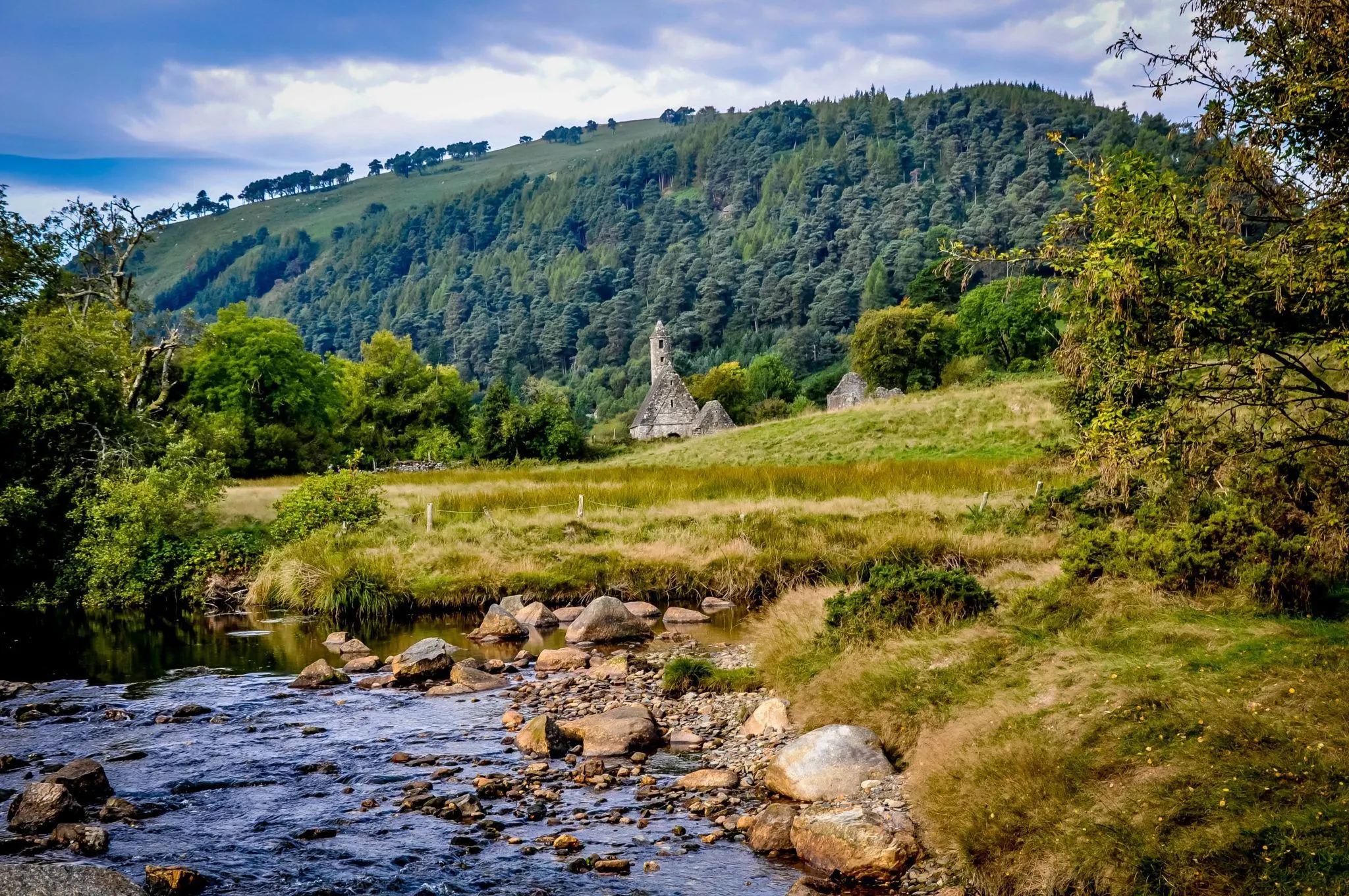 Ancient stone building at the base of a mountain close to a stream