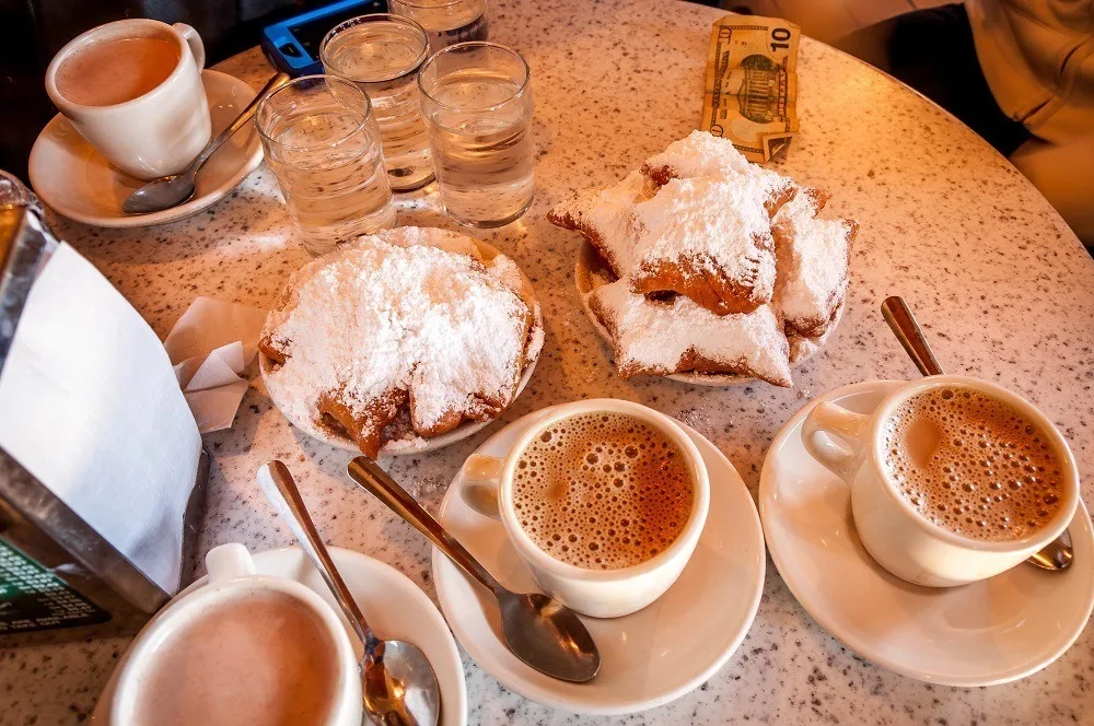 Beignets and coffee on a table.