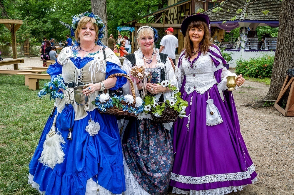 Women dressed in Renaissance-era dresses carrying baskets of flowers