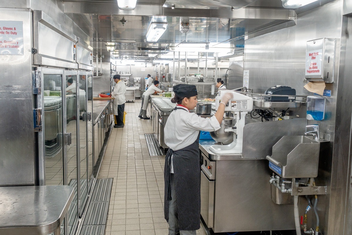 Kitchen employee using a stand mixer in the ship's galley