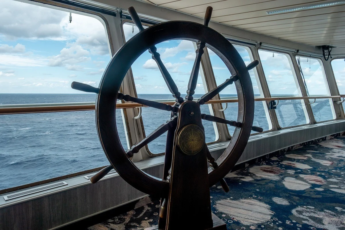 Steering wheel on the ship's bridge overlooking the ocean
