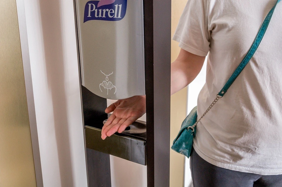 Person with their hand under a Purell hand sanitizer pump