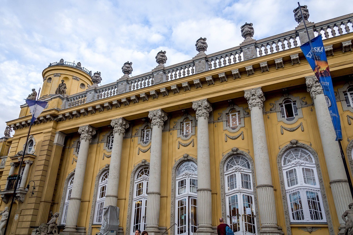 The white columns and yellow building of Szechenyi, one of the Budapest baths