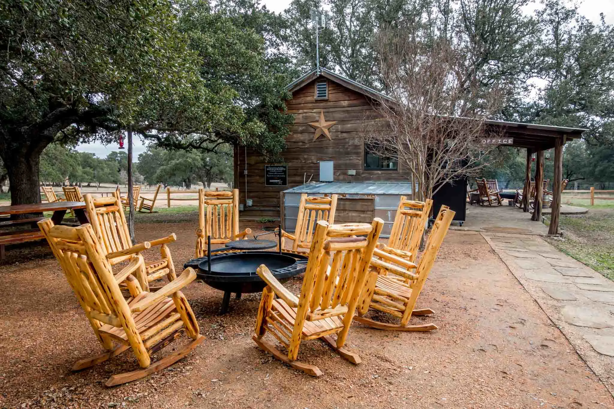 Rocking chairs around fire pit outside a wooden building