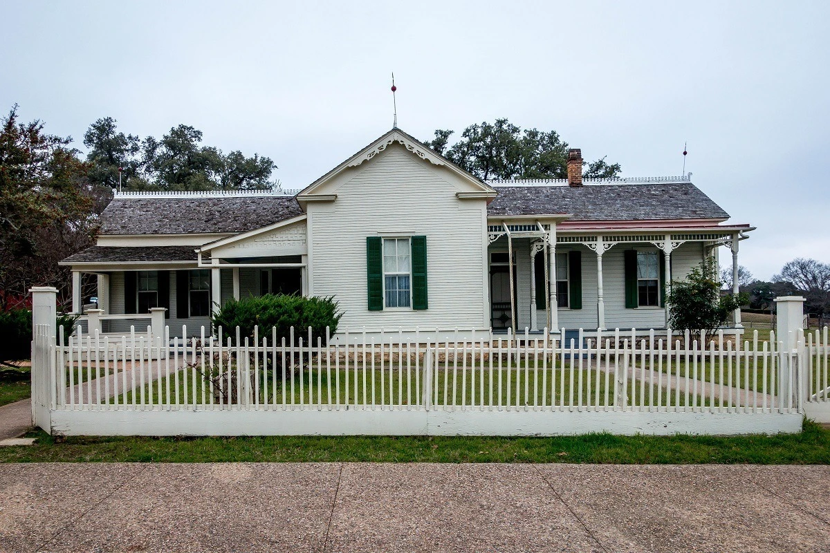 Exterior of a white house with a picket fence.