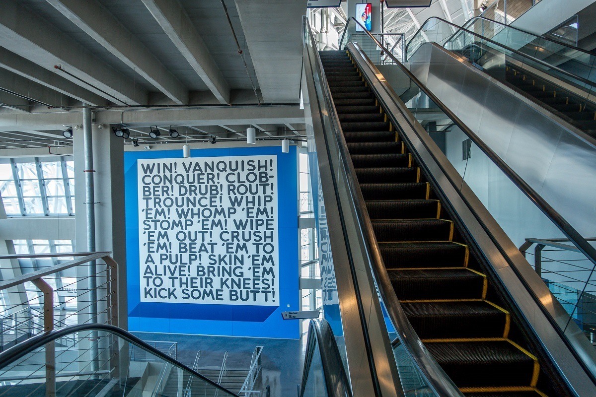 Word-based artwork hanging near escalators