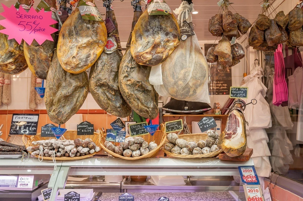 Charcuterie and cured meats displayed in a market stall