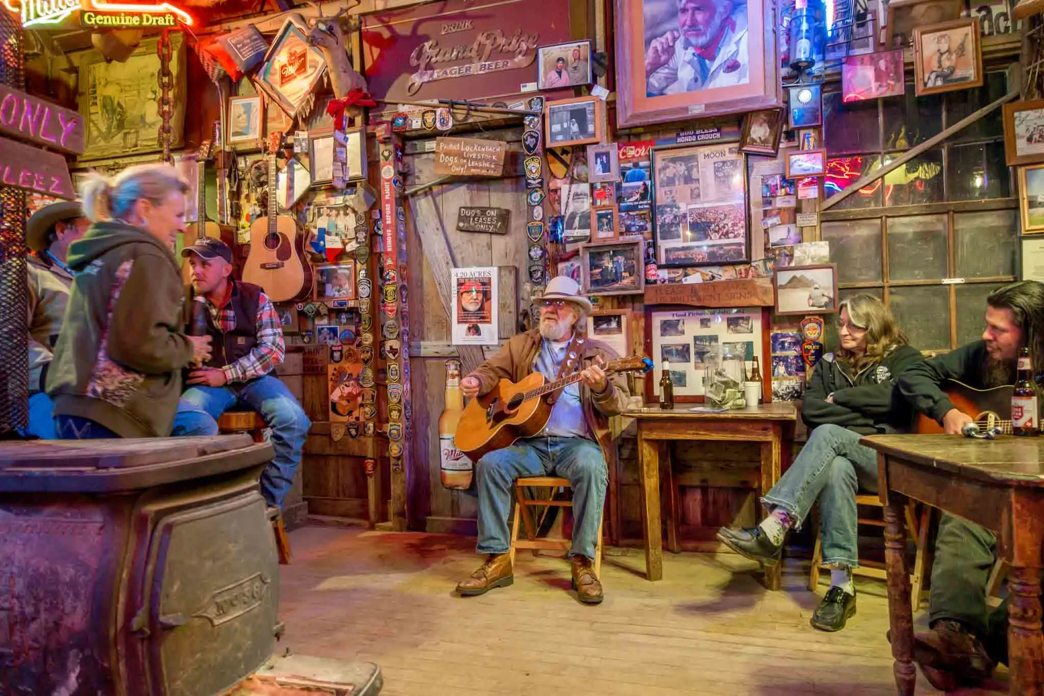 People watching a man play guitar in a bar with walls covered in memorabilia