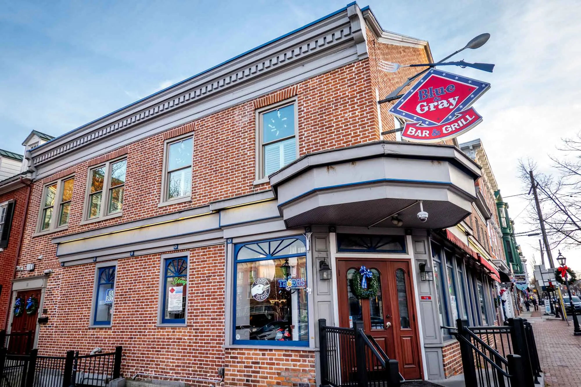 Exterior of a red brick building with a red sign for the Blue and Gray Bar & Grill