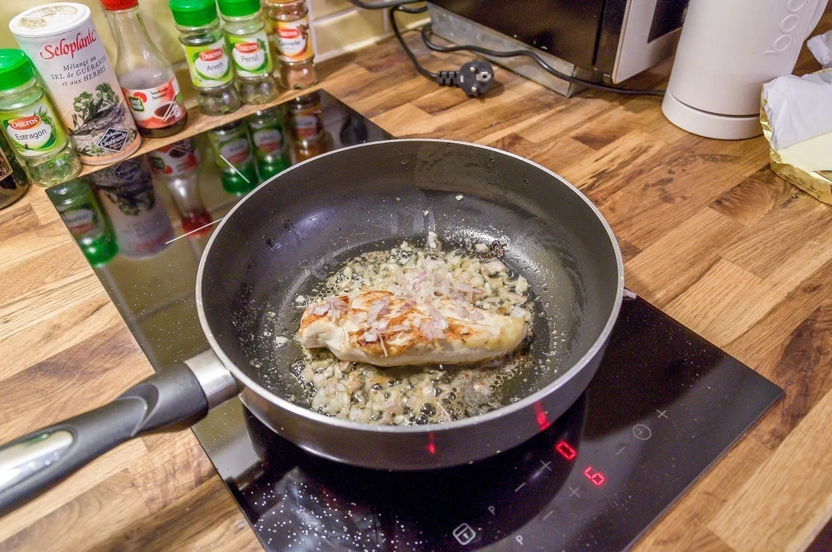 Chicken breast cooking in pan on stove