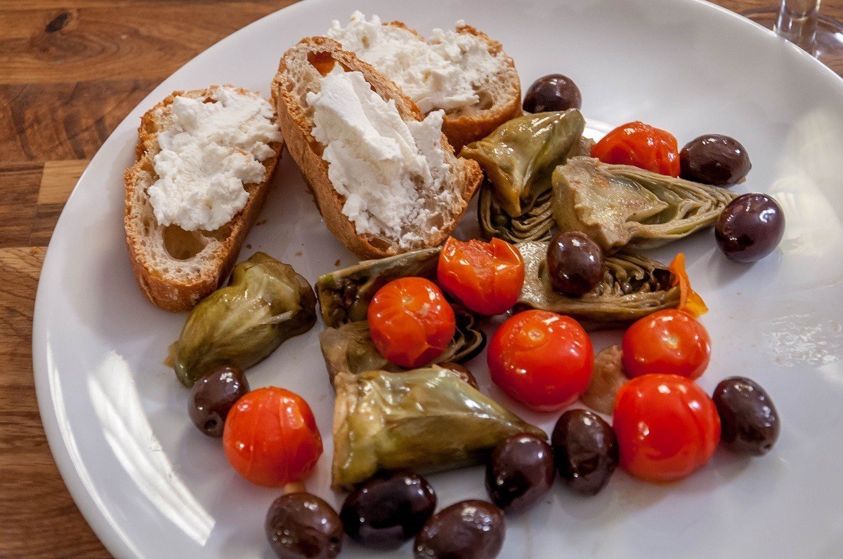Artichokes Provencal with baguette and goat cheese on plate