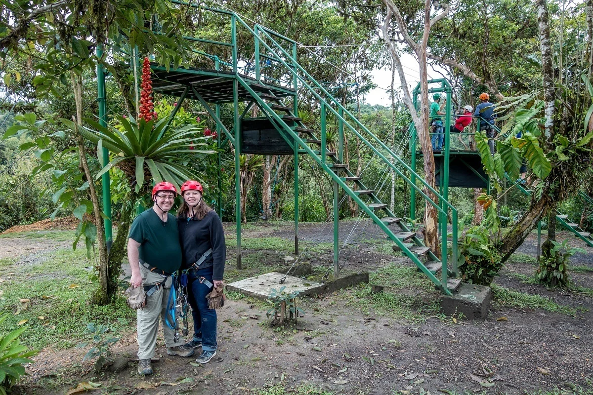 People standing near zipline ladders surrounded by vegetation