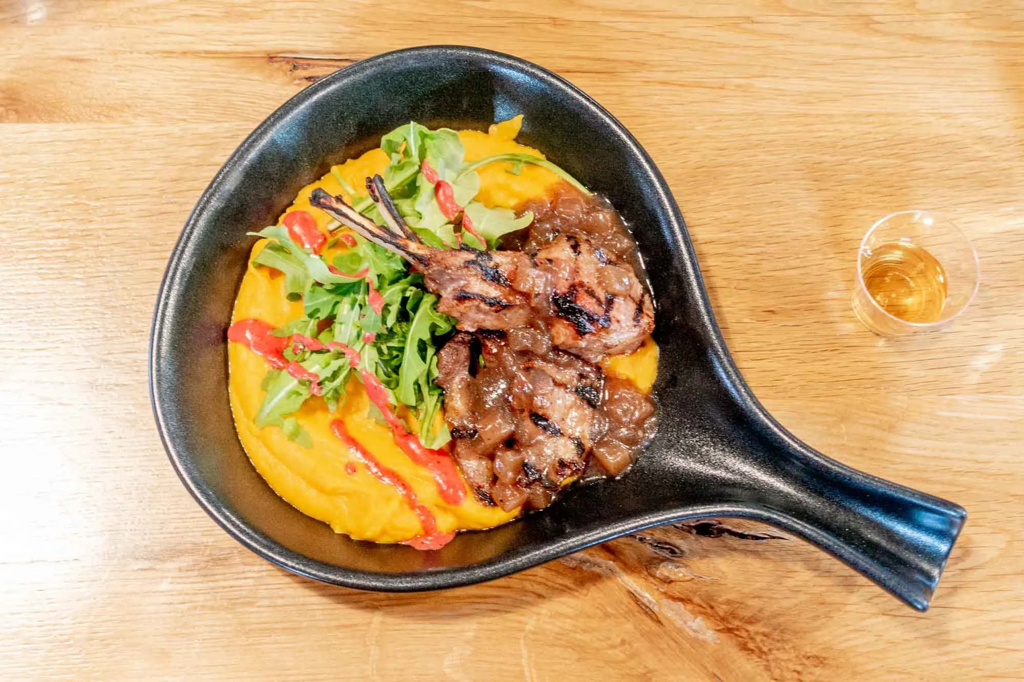 Lamb chops on top of sweet potatoes in a skillet