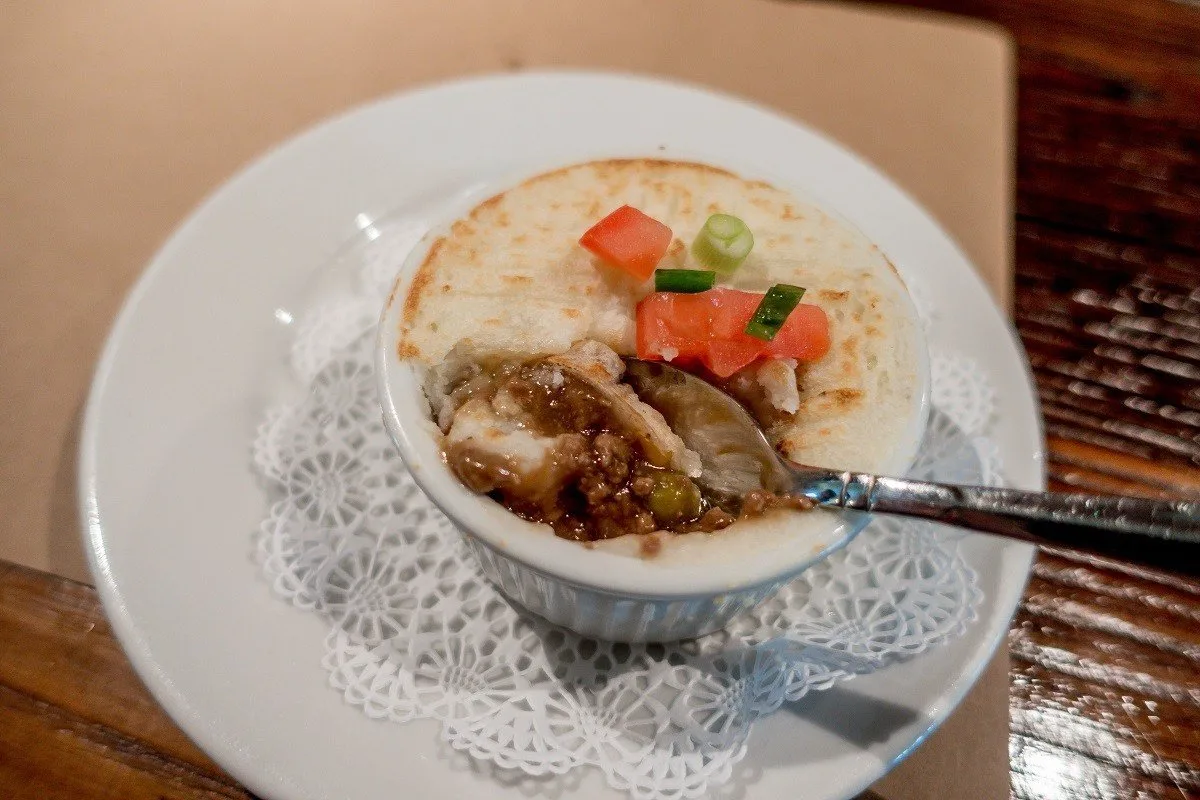 Spoon in a dish of shepherd's pie topped with mashed potatoes