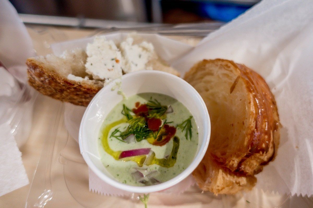 Cup of cucumber gazpacho beside two slices of bread