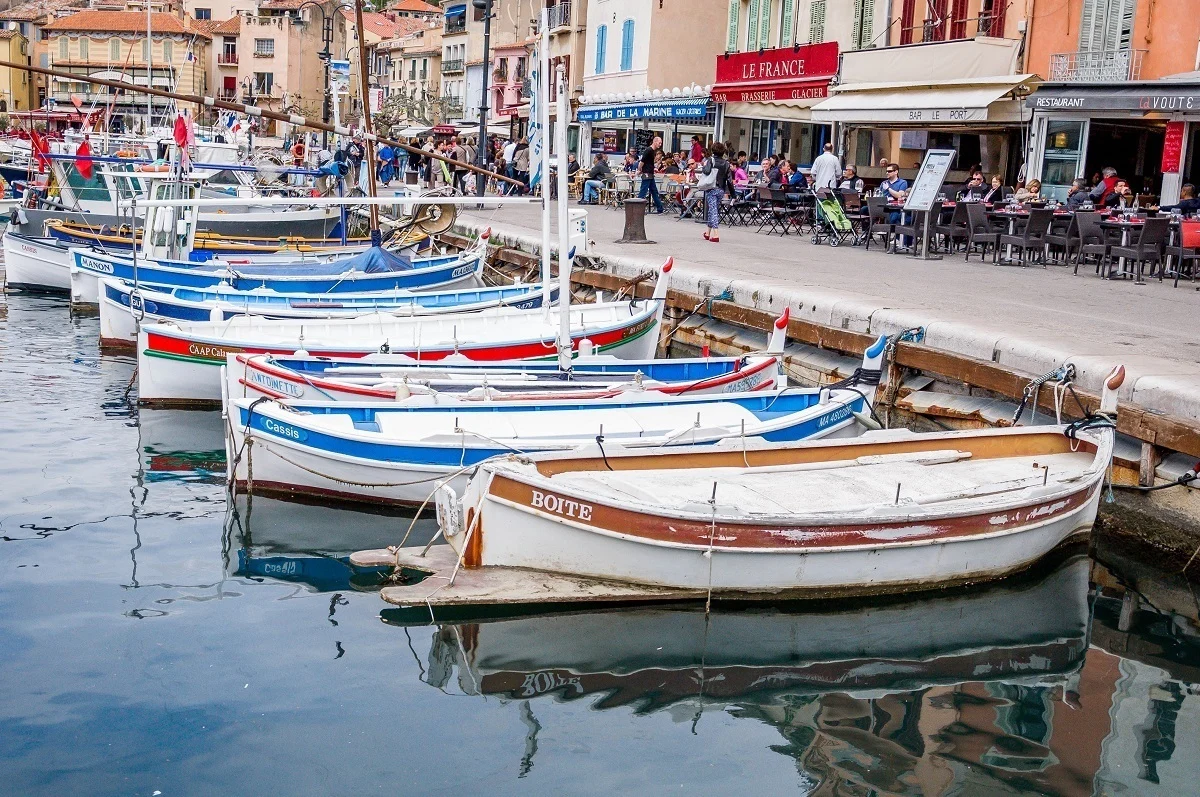 Boats docked in the harbor of Cassis in front of waterfront restaurants