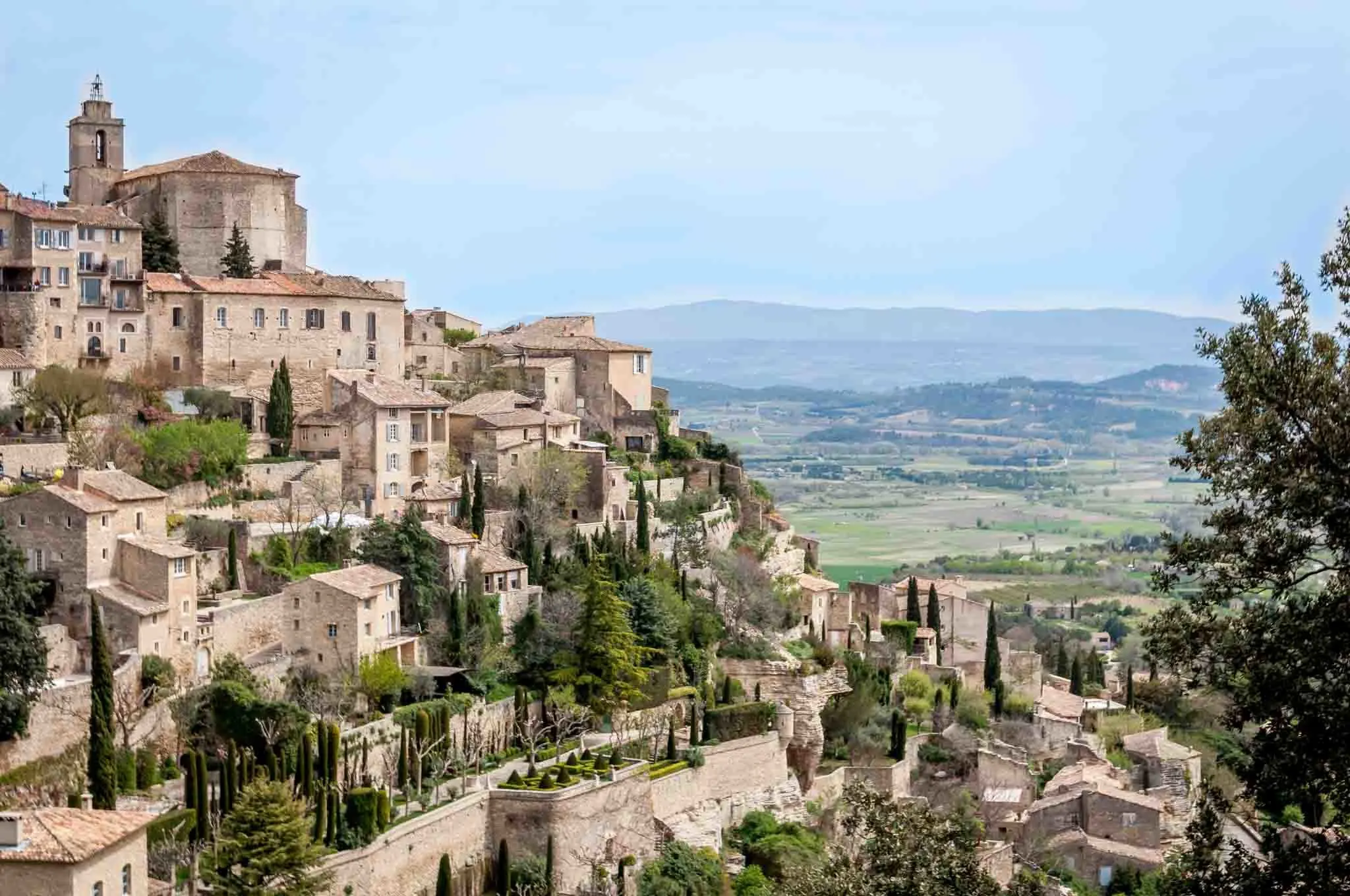 Stone buildings on a mountainside descending to a valley in Gordes
