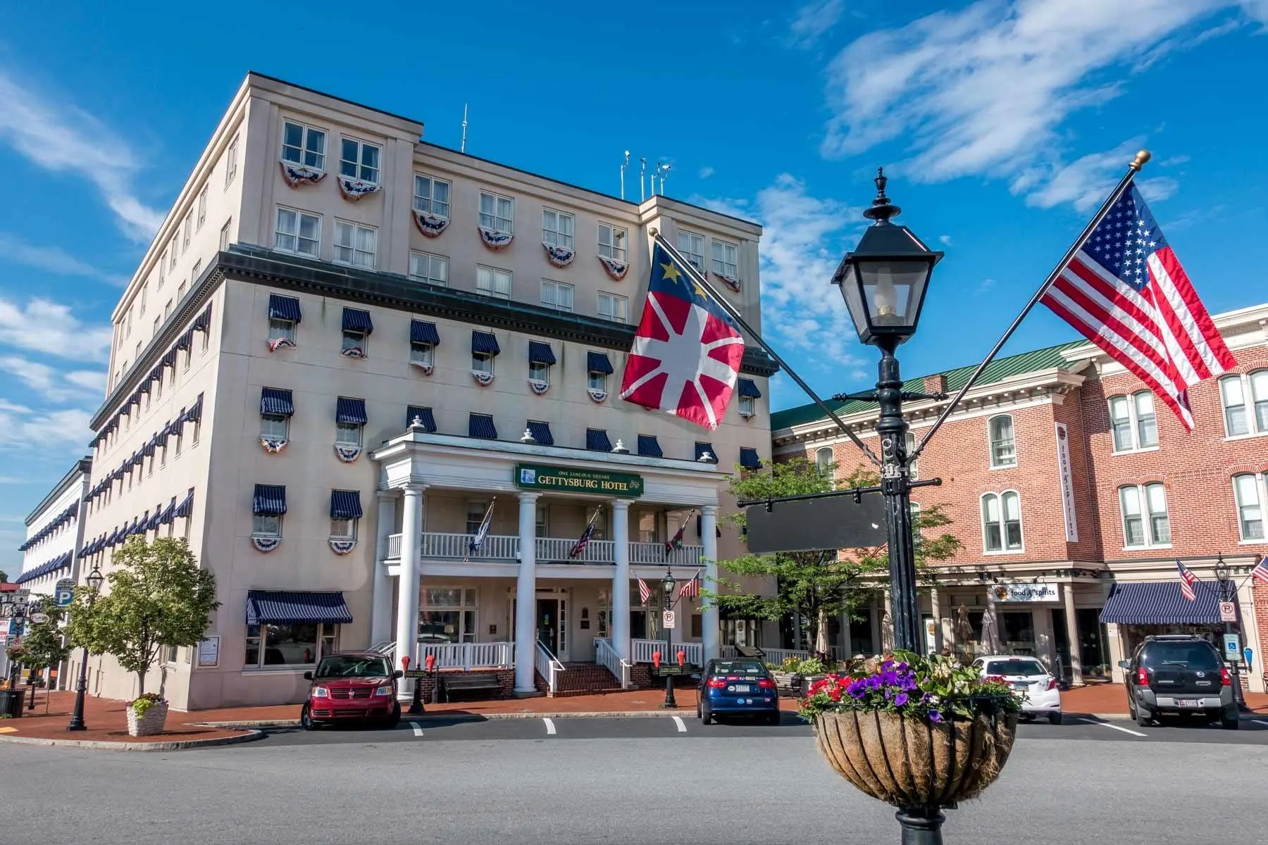 Flags flying in front of a 6-story building with rows of windows and a sign: Gettysburg Hotel
