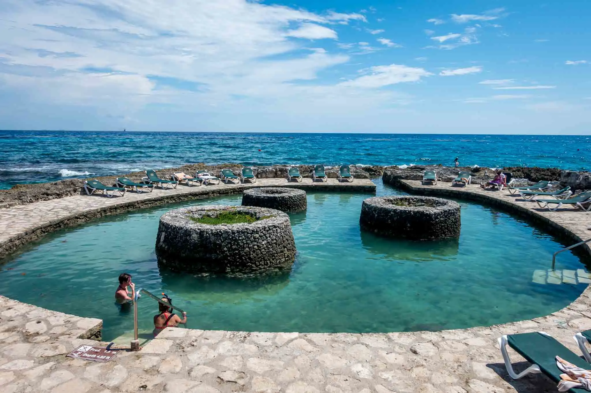 Two people in a circular pool by the ocean