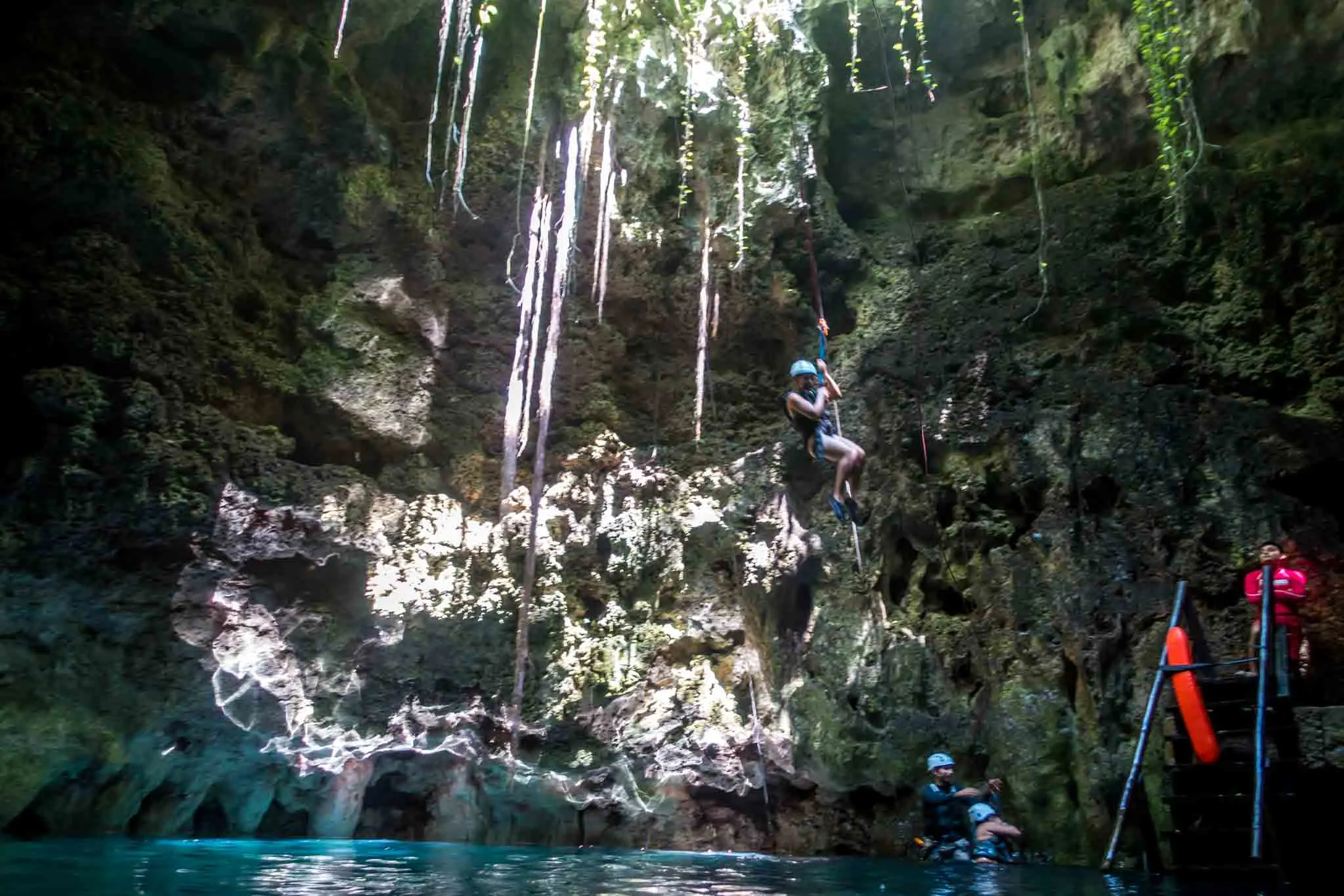 People rappelling into a cave cenote near Cancun
