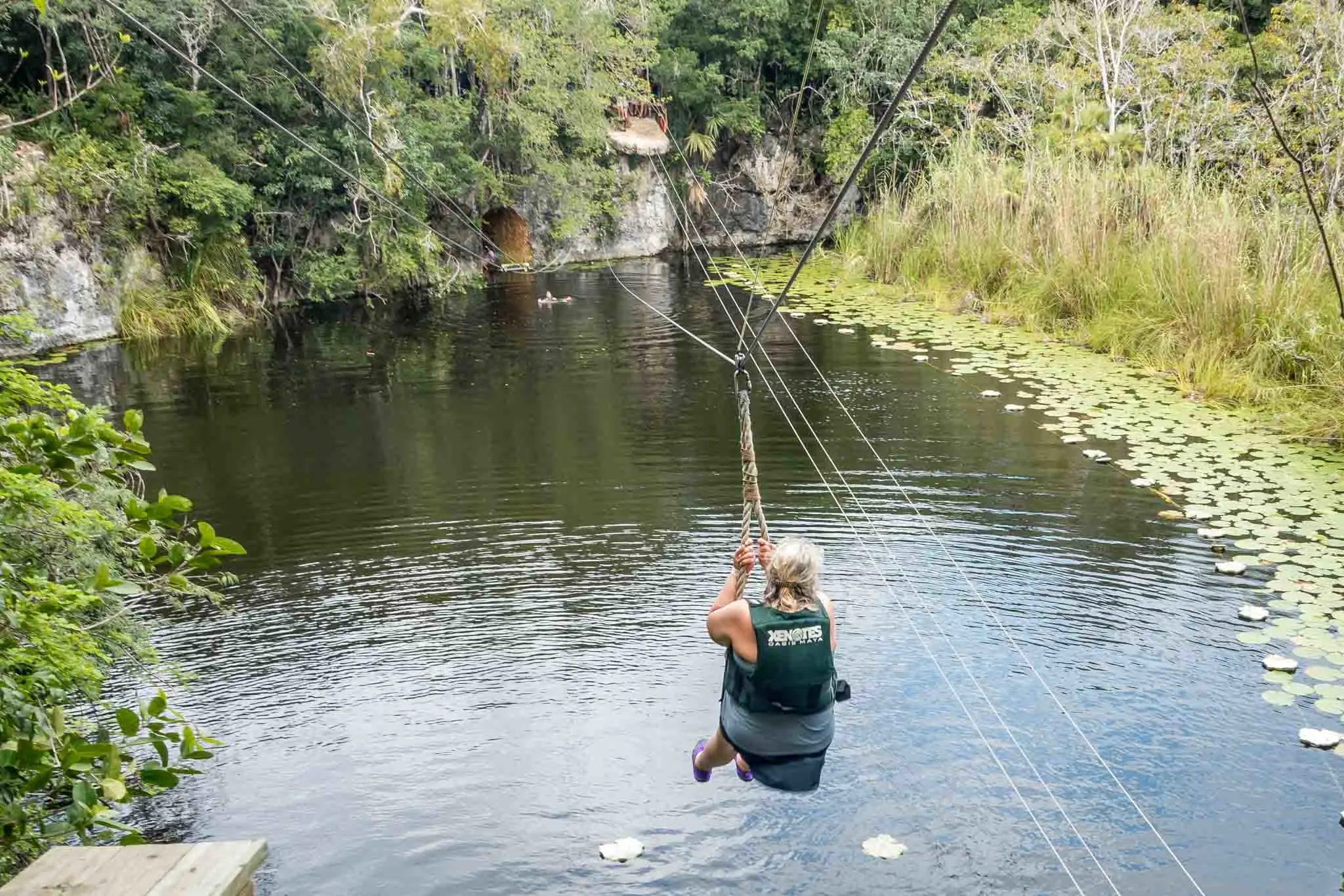 Woman zip lining into the water on a Xenotes Oasis Maya tour