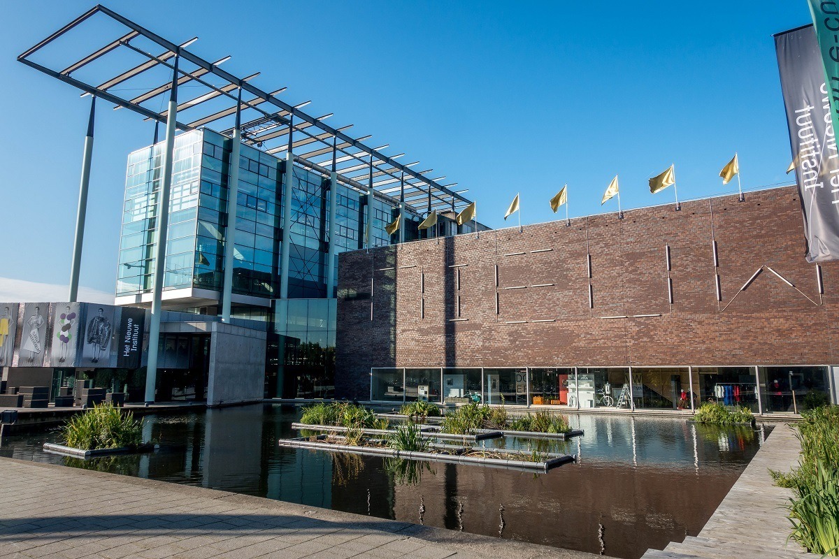 The New Institute building with glass walls and a small pond