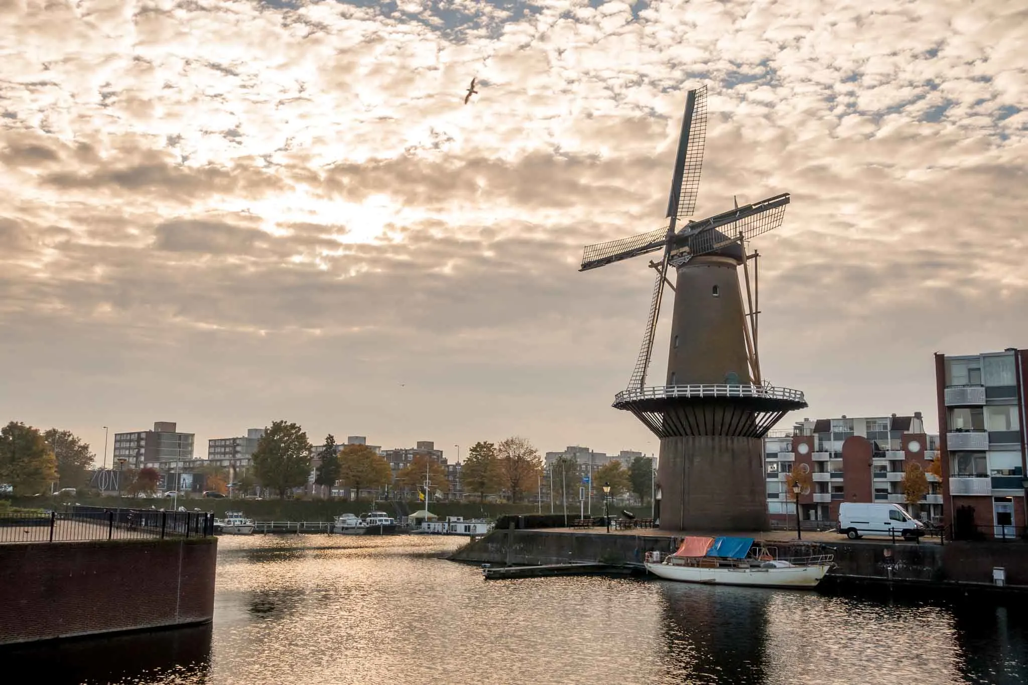 Windmill by the water beside modern apartment buildings 