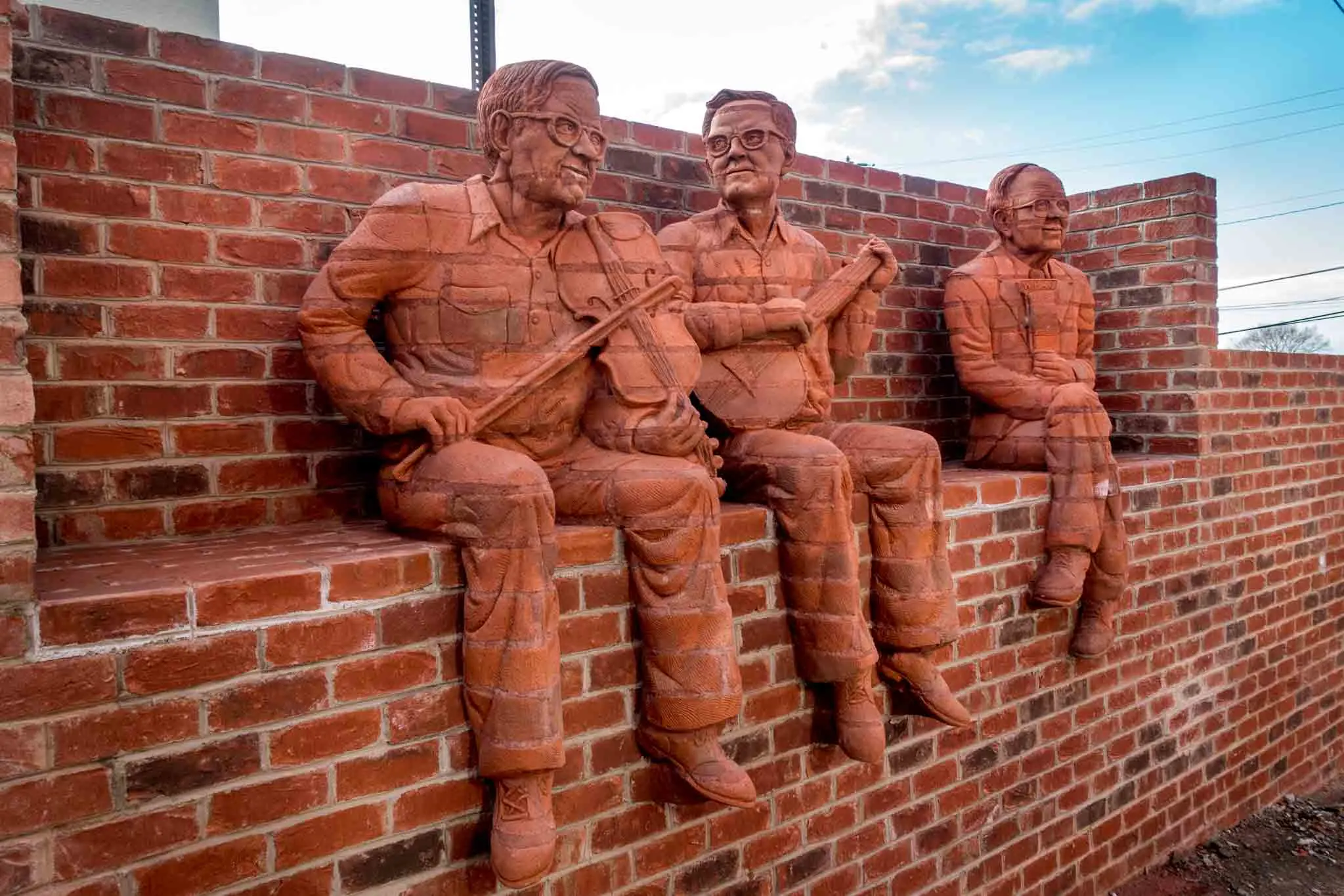 Brick sculptures of musicians sitting on a wall