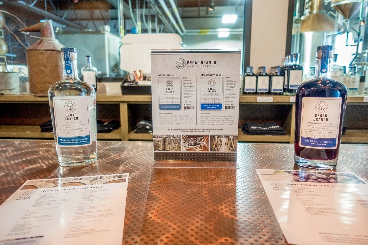 Two liquor bottles and a sign on a bar