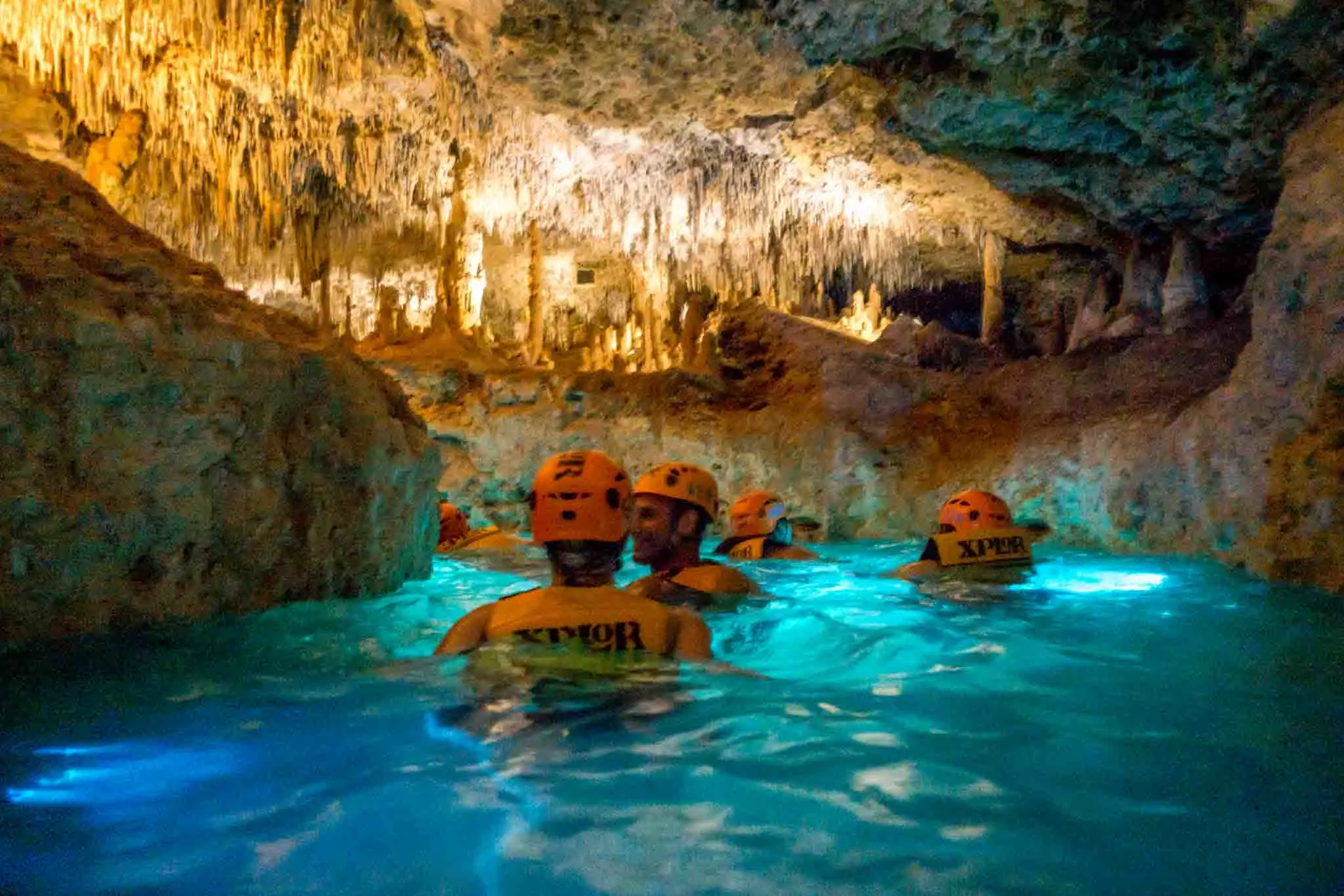 People wearing helmets while swimming in an underground river 