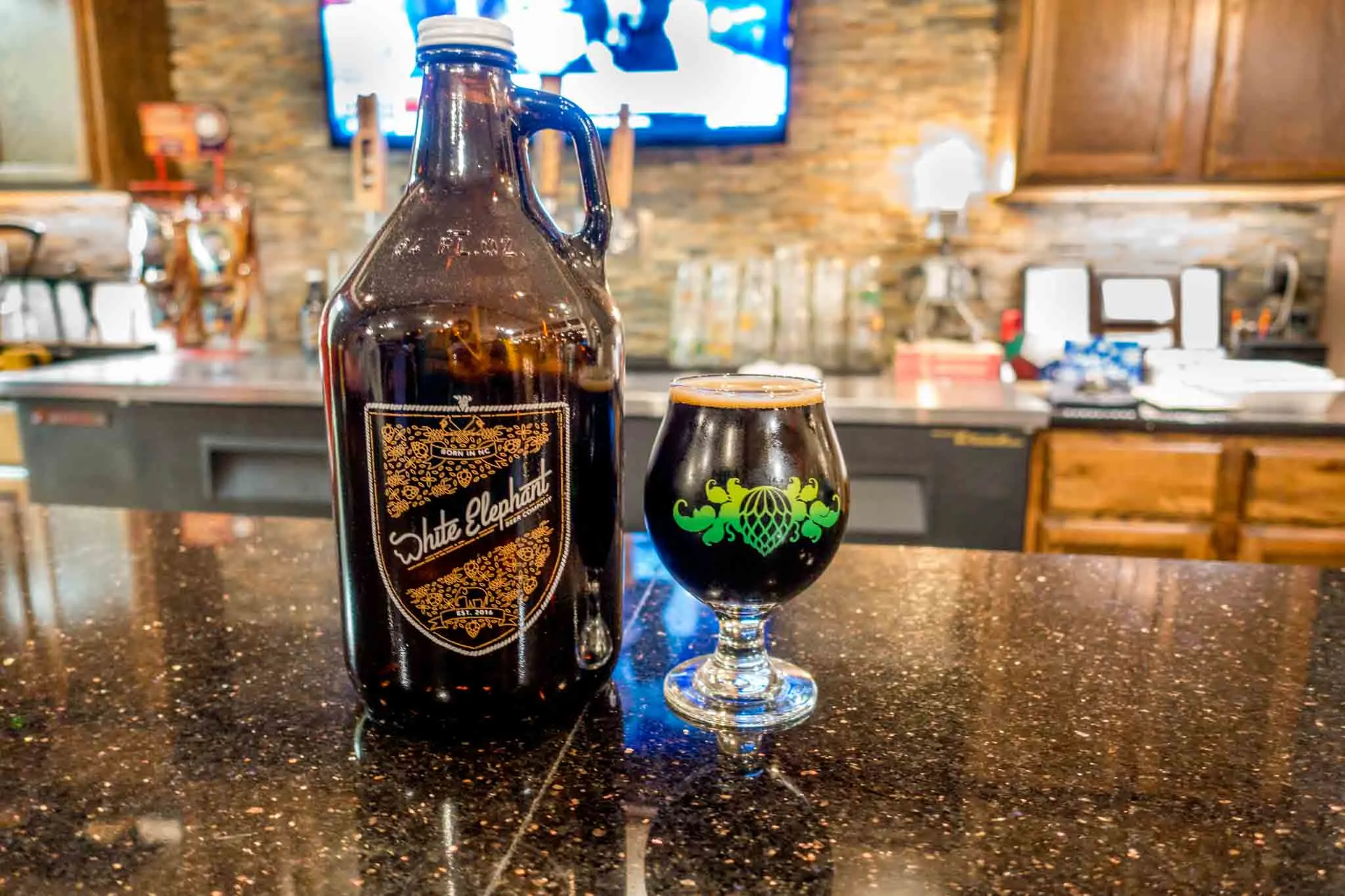 Growler and pint glass on the bar at White Elephant Beer Company