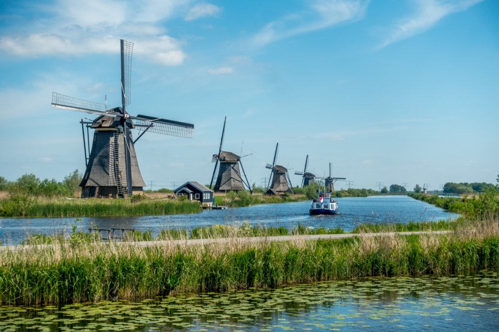 Five windmills with a boat passing by in the canal at Kinderdijk