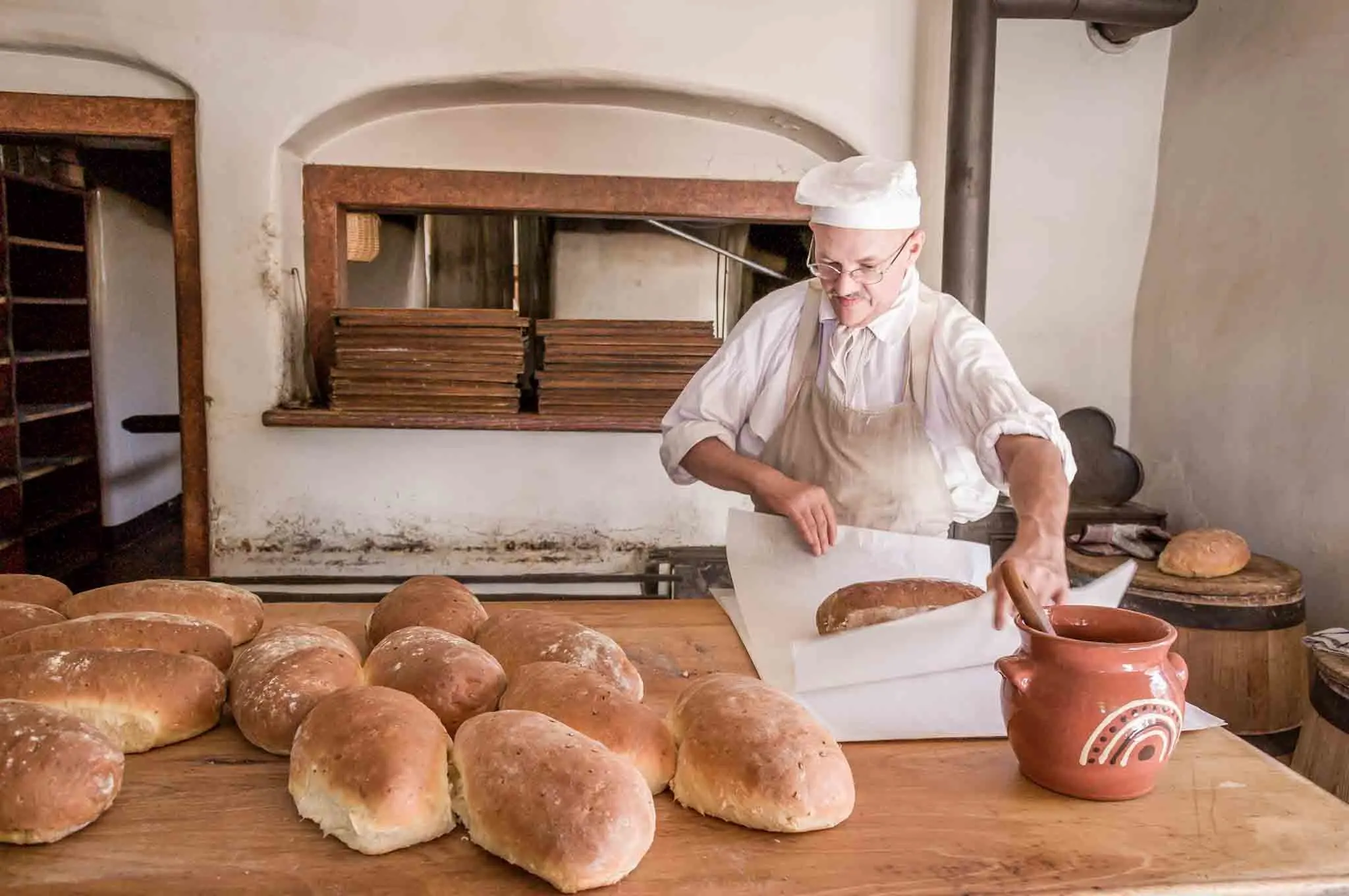 Baker buttering and wrapping bread at Old Salem.