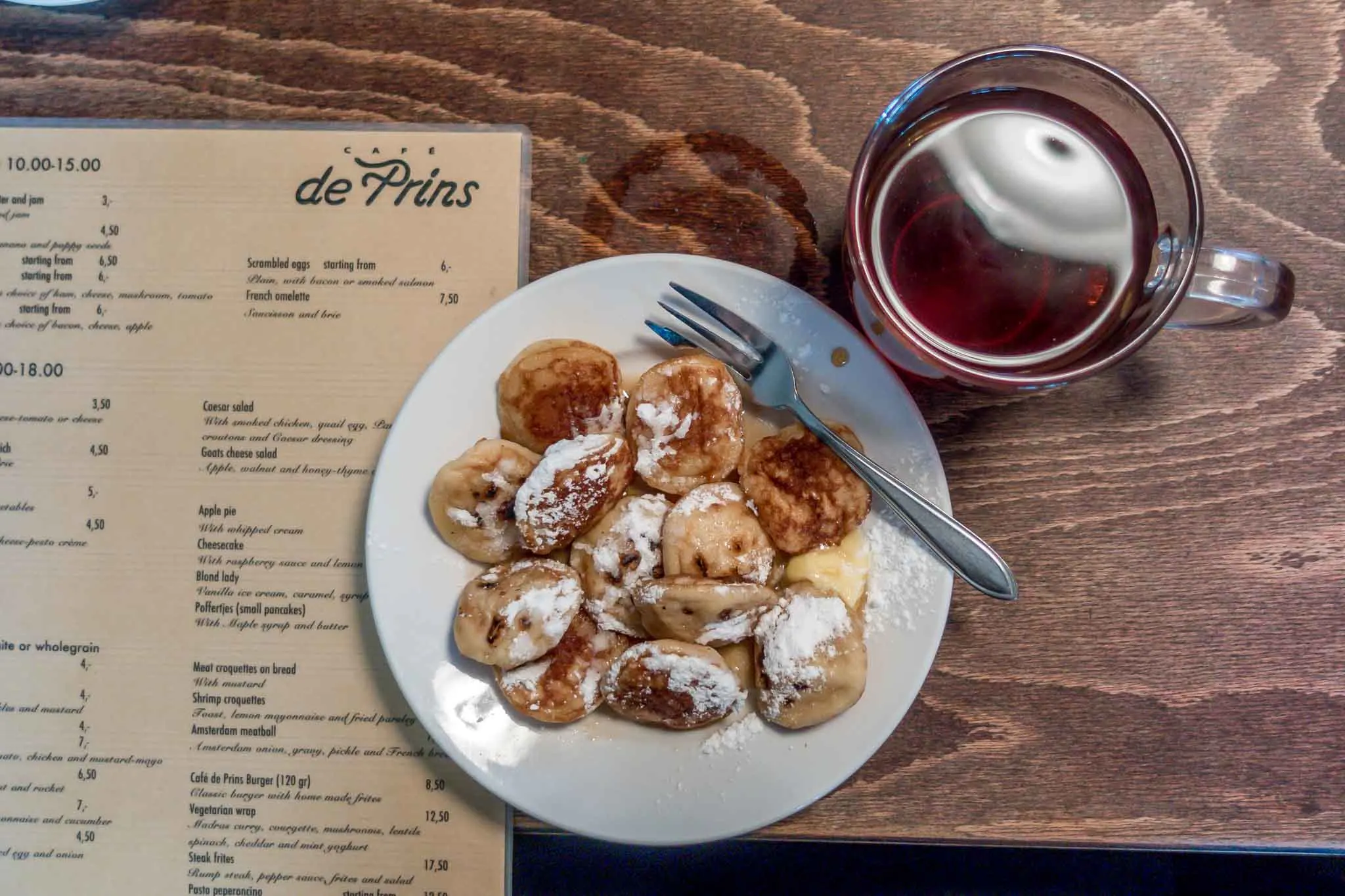 Plate of small puffy pancakes with a cup of tea and a menu