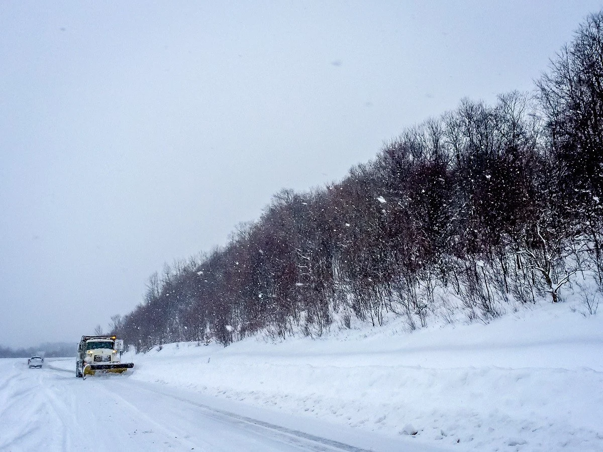 Snow plow driving on a snow-covered highway