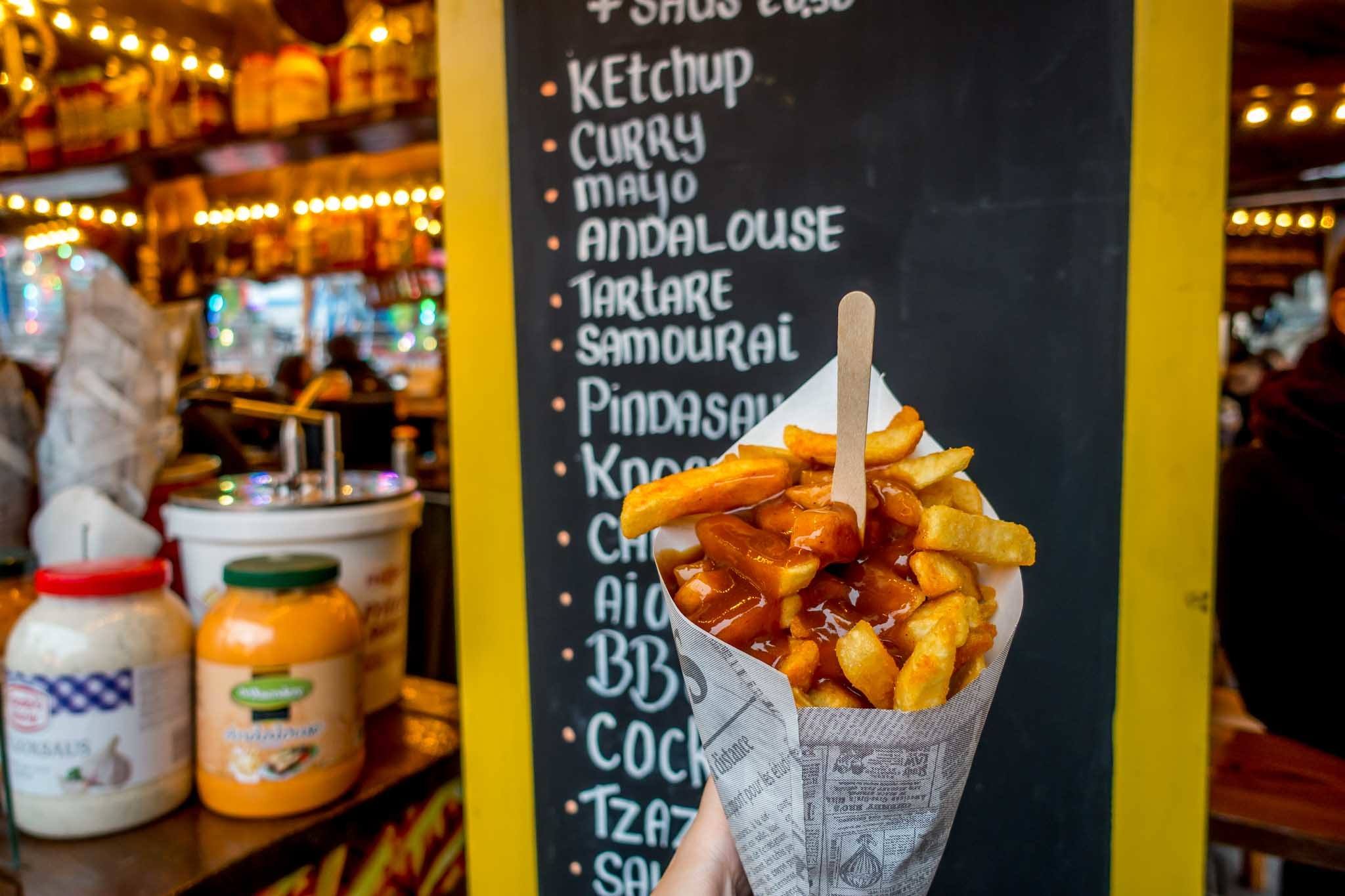 French fries in front of a sign listing sauce choices at a Christmas market