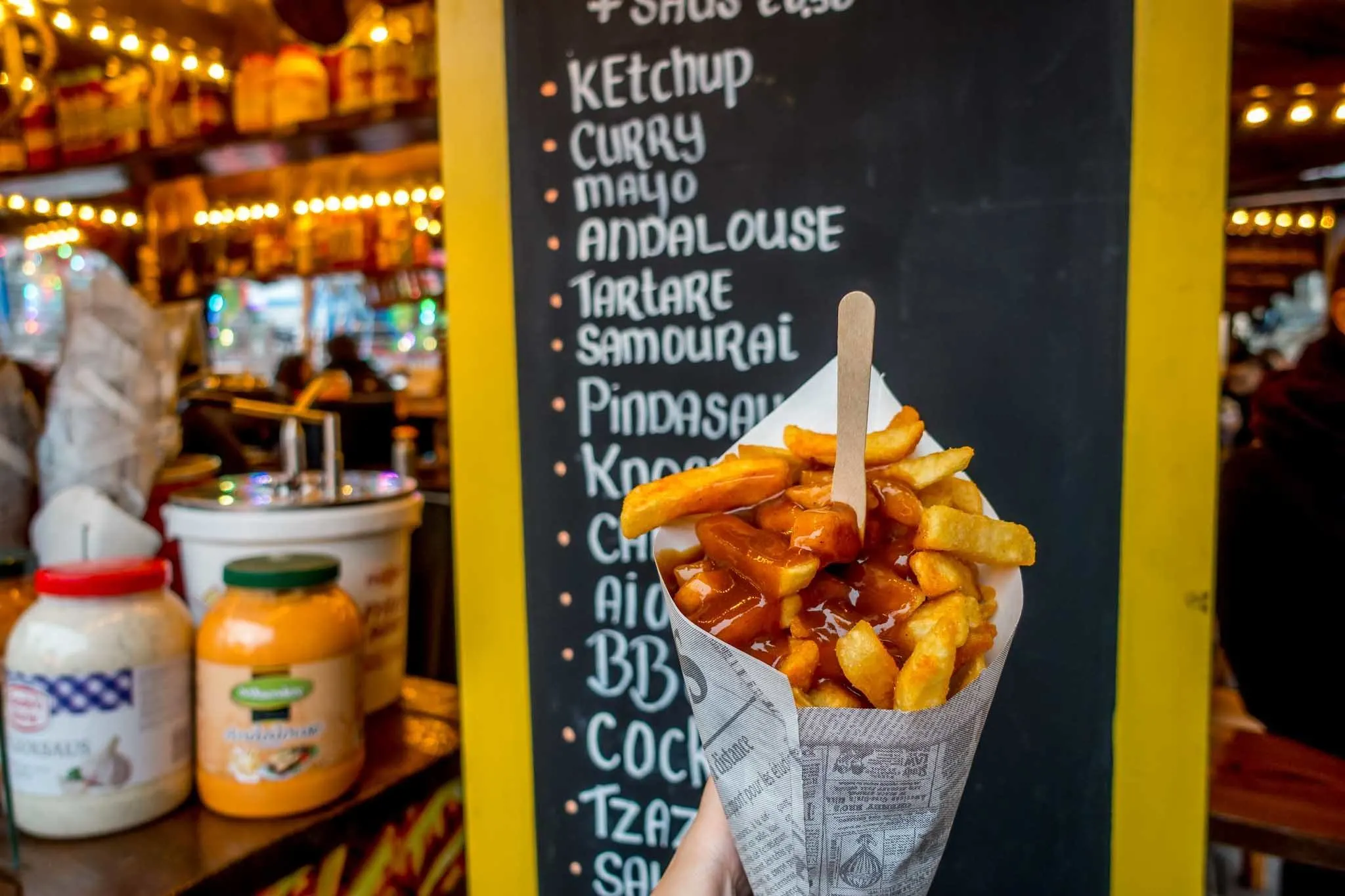 French fries in front of a sign listing sauce choices at a Christmas market.