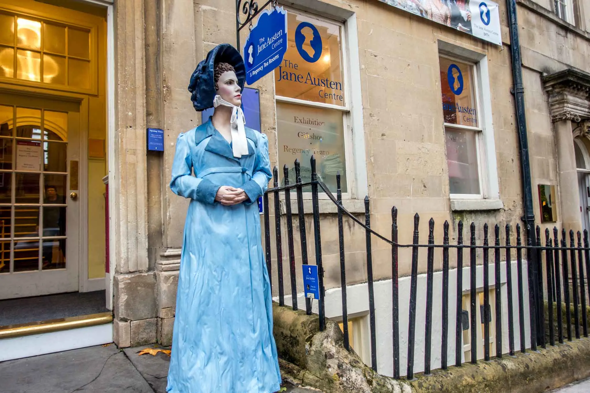 Statue of a woman in a blue dress in front of the Jane Austen Center.