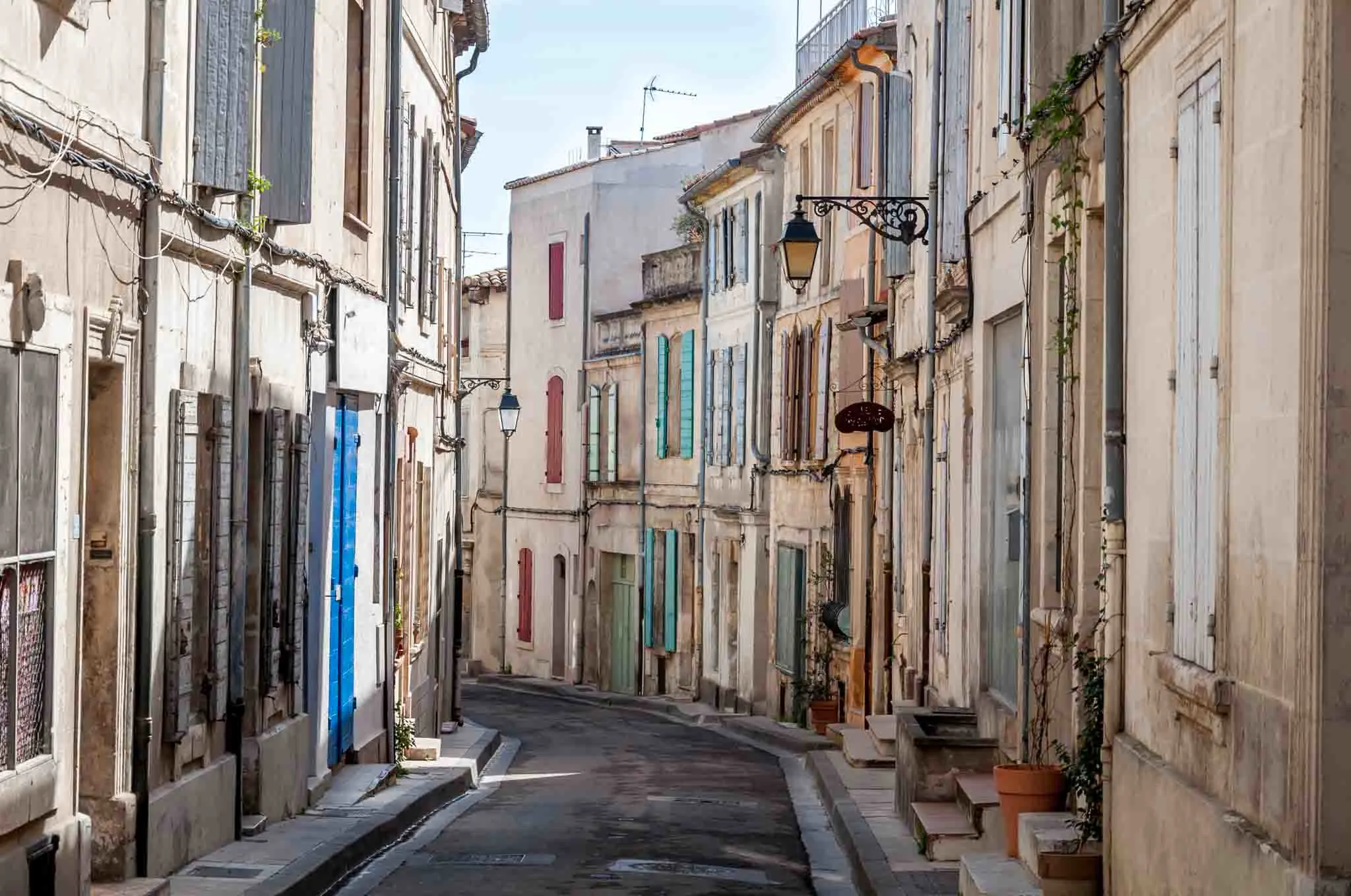 Curving street full of homes with colorful shutters. 