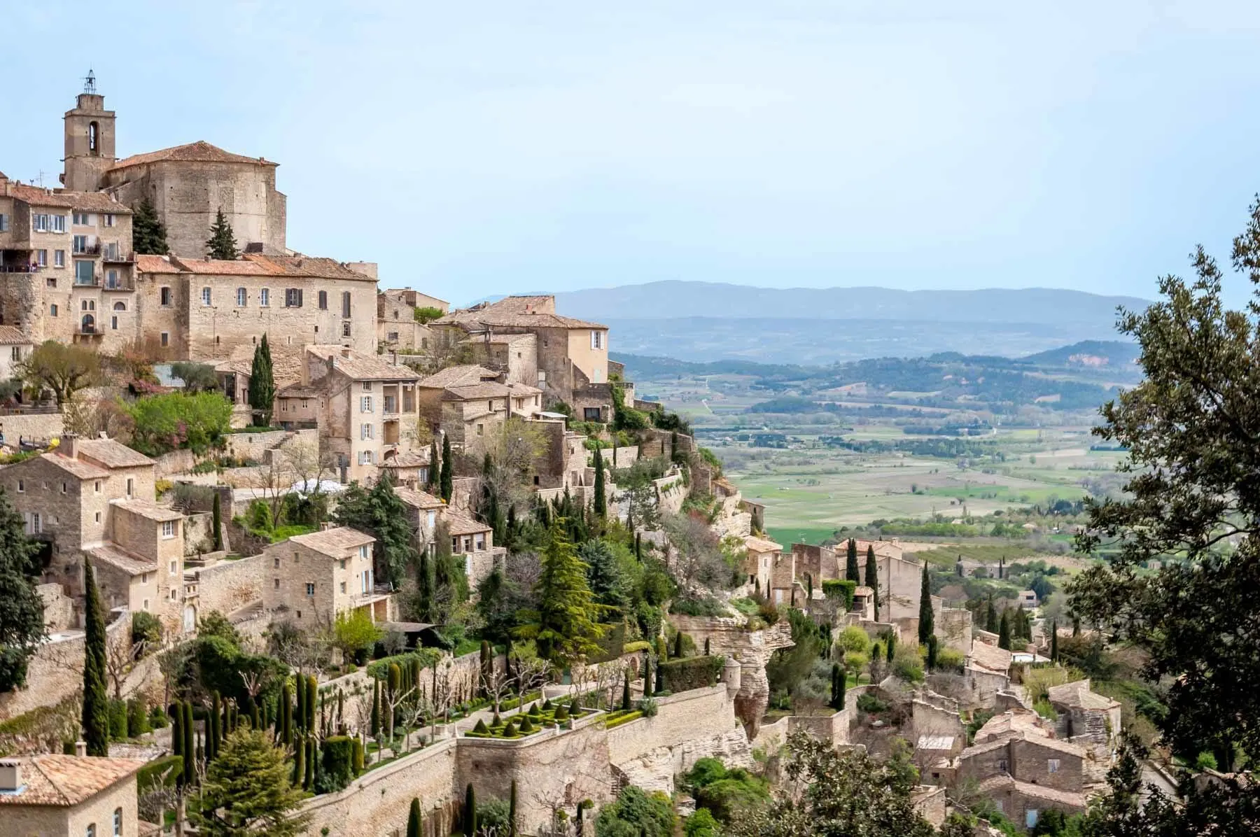 Hillside village with stone buildings and trees overlooking a valley