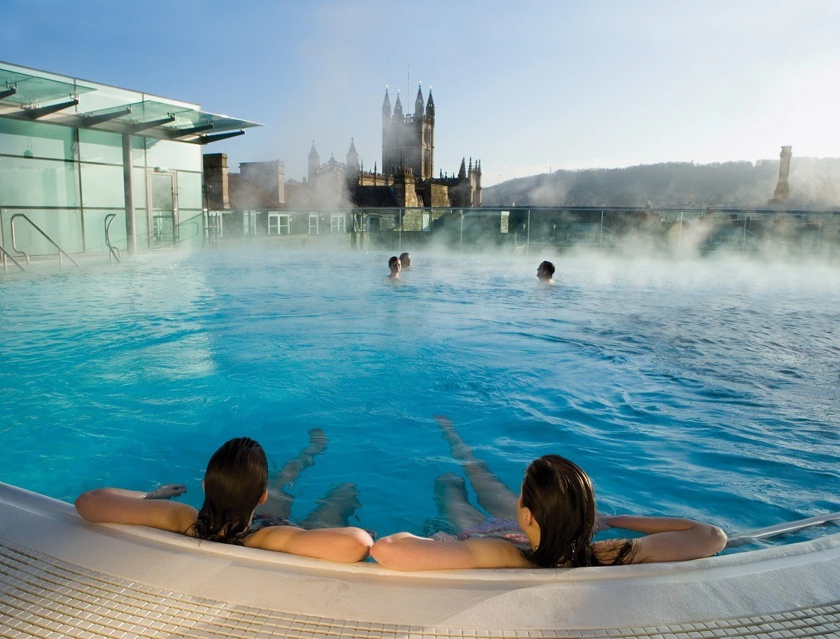 Bathers in the rooftop pool at the Thermae Spa with Bath Abbey in the distance