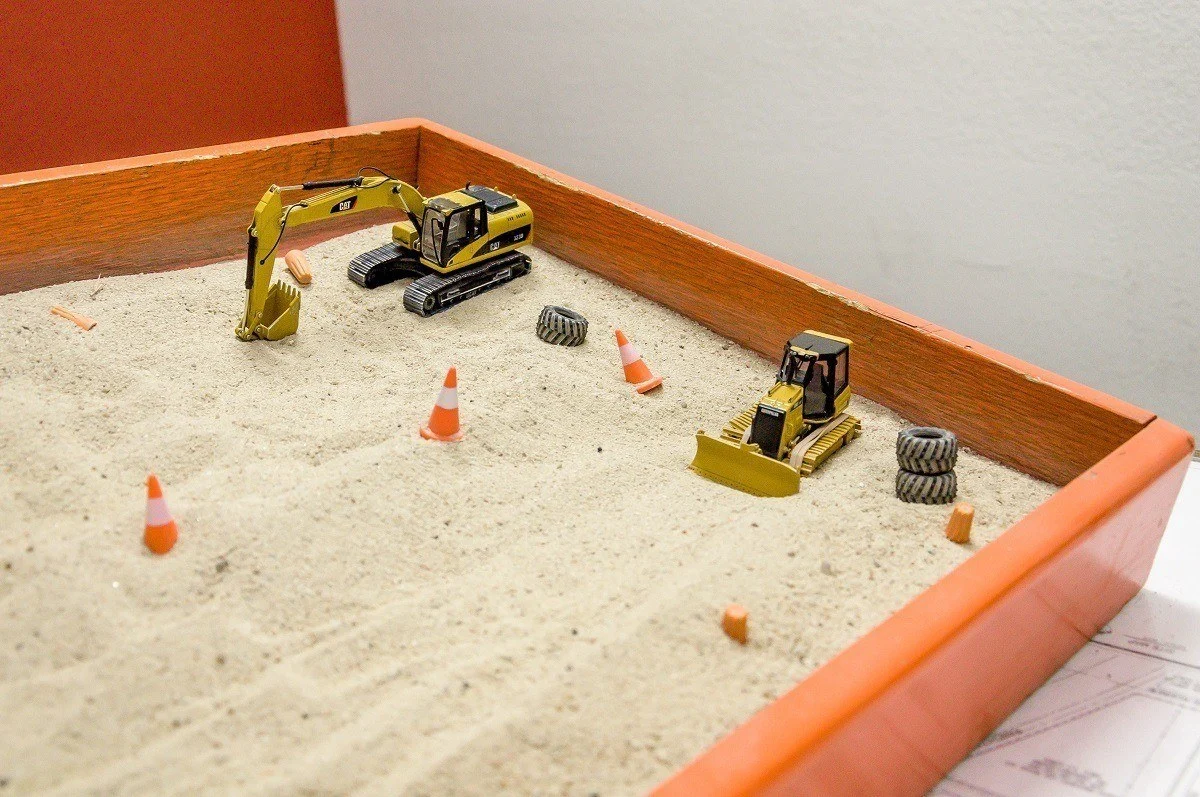 Construction equipment in a sandbox for a safety demonstration model