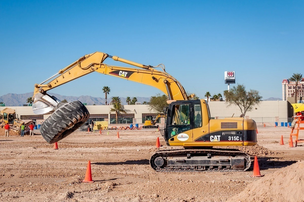 Excavator carrying tires across the sandbox at a construction playground