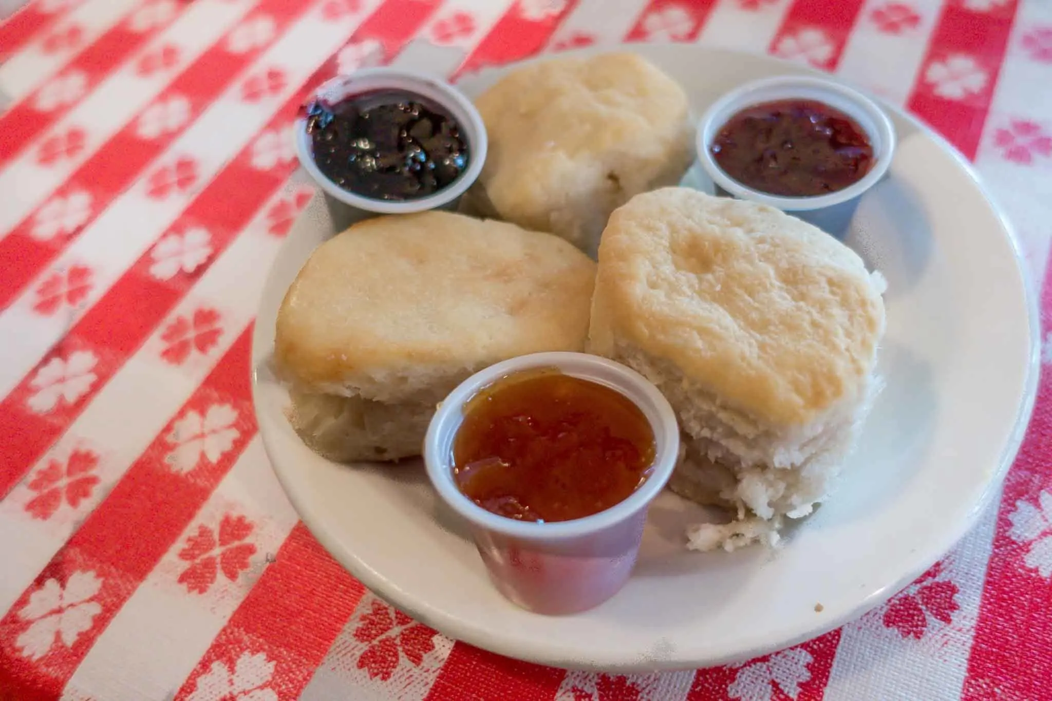 Biscuits on a plate with three kinds of preserves